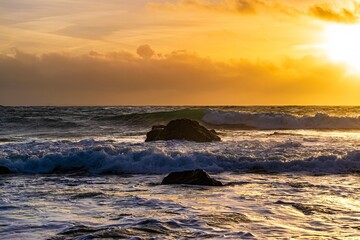 sunset over the sea and waves dashing against rocks