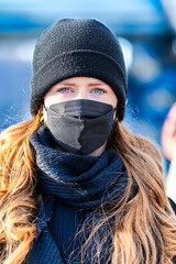 Woman with long red hair and a hat wears an FFP 2 protective mask.