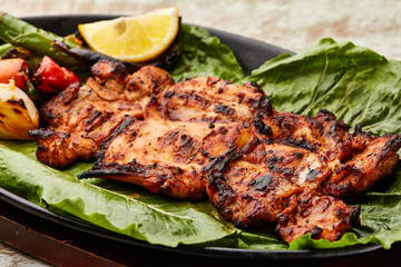 Grilled Chicken with lemon slice and tomato served in dish isolated on table top view of arabic food