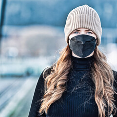 Woman with long red hair and a hat wears an FFP 2 protective mask.