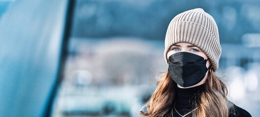 Woman with long red hair and a hat wears an FFP 2 protective mask.