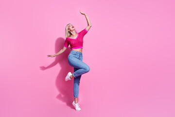Full size photo of carefree good mood woman dressed knit top denim pants raising palm up look empty space isolated on pink background - obrazy, fototapety, plakaty