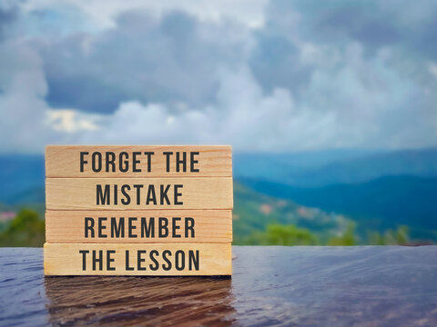Inspirational life quote. Forget the mistake, remember the lesson text on wooden blocks with nature background. Stock photo.