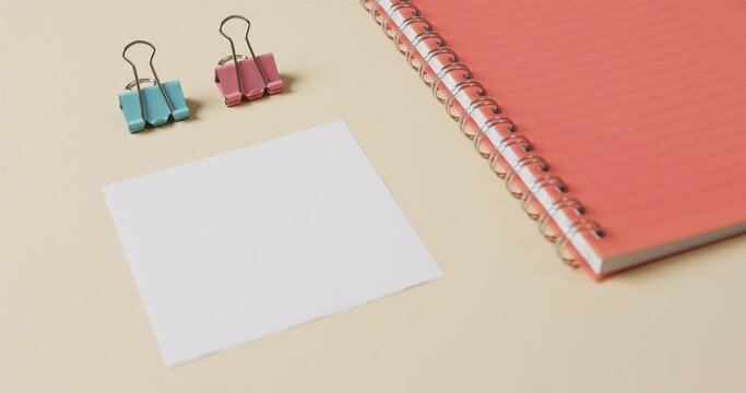 Close up of red notebook and school stationery arranged on beige background, in slow motion