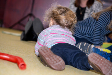 petite fille blonde allongée au sol sur une moquette dans un salon