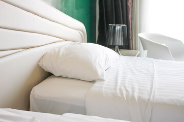 Interior of a hotel bedroom with white bed and white table lamp