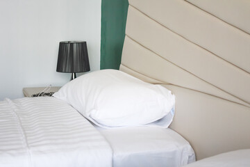 The double bed has two pillows and white sheets and a cushioned headboard.