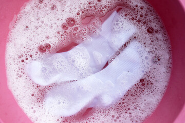 Dirty socks soaked in water, dissolving detergent in basin.