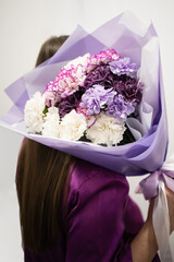 Woman making fashion modern bouquet in korean style from different flowers carnations, flower mixture of flowers. A bouquet of flowers is a surprise for the holiday. Flower delivery, florist, courier