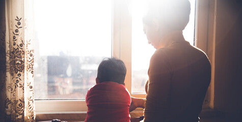 a woman and a child looking out a window