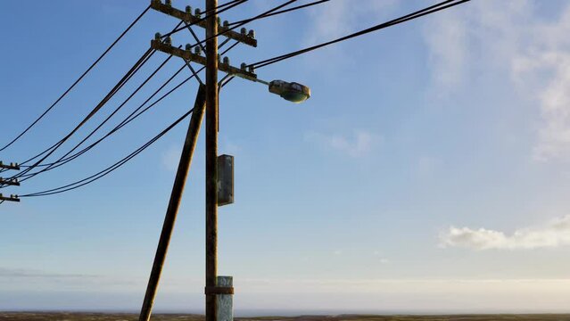An up-close look at aging telephone wires, electricity cables, and street lights hanging from old wooden utility poles.