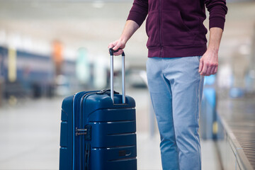 Passenger traveling by plane picking up blue suitcase from conveyor belt in airport arrivals...