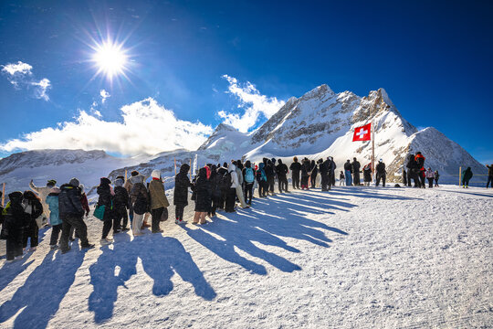 Tourists waiting in line to take a photo in front of Swiss flag on Jungfraujoch peak
