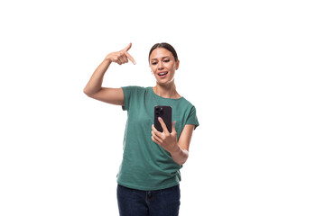 30 year old slender brunette woman with collected hair dressed in a green basic T-shirt takes a selfie on the phone