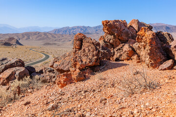 Red rocks near the road in the dry, hot rocky Mojave Desert in California at the entrance to Death...