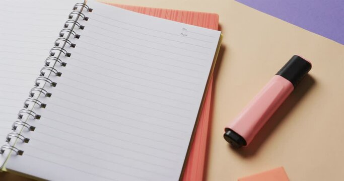Close up of open notebook with school stationery on beige and blue background, in slow motion