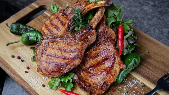Lamb pork chops grilled with fresh salad on wooden cutting board rotate. Loin on ribs. Top view