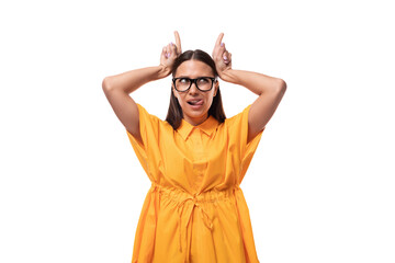 Caucasian young woman with black straight hair wears glasses and a yellow dress