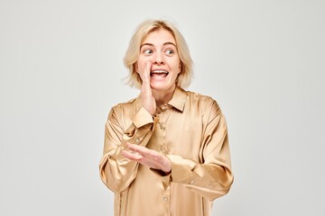 Portrait of blonde girl shouting loudly with hands, news, palms folded like megaphone isolated on white background - obrazy, fototapety, plakaty