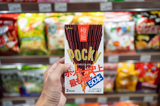 PENANG, MALAYSIA - MAY 15, 2023: Hand holding a Alico Pocky chocolate biscuit stick on grocery shelf background.