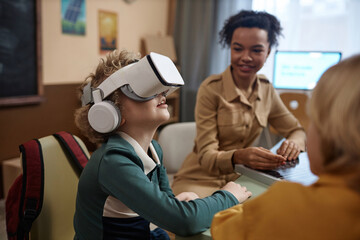 Side view portrait of little boy wearing VR headset enjoying immersive experience in modern school...