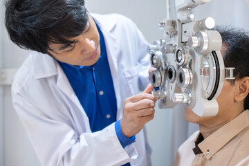 Optometrist uses ophthalmological diagnostic equipment to test the vision of an elderly man,...