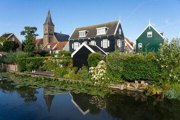 Obraz premium View of the beautiful and typical fishing village of Marken in Netherlands at sunset reflected on a canal.