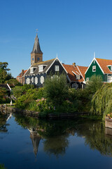 Fototapeta na wymiar View of the beautiful and typical fishing village of Marken in Netherlands at sunset reflected on a canal.