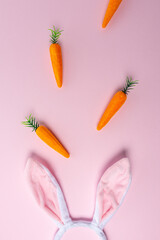 Pink bunny ears with carrots on pink background. Minimal Easter concept.