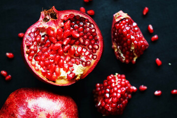 Cut pomegranate next to a whole one on a dark background