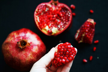 Cut pomegranate next to a whole one on a dark background