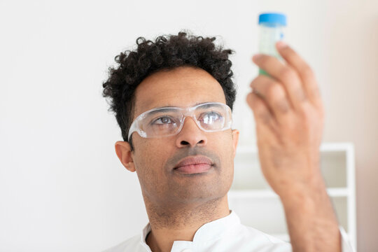 Scientist with lab glasses checking a liquid sample