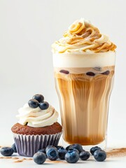Iced coffee with milk and blueberry cupcake on white background.