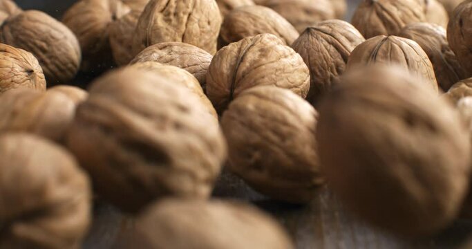 Super slow motion macro of fresh bio organic dried walnuts are falling on wooden rustic table in kitchen of restaurant at 1000 fps.