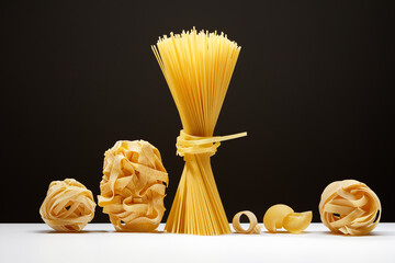 Variety of types and shapes of Italian pasta on a black and white background. Italian egg pasta...