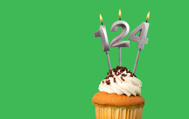 Birthday with number 124 candle and cupcake - Anniversary card on green color background