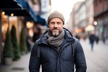 Portrait of a handsome middle-aged man in a hat and coat walking on a city street