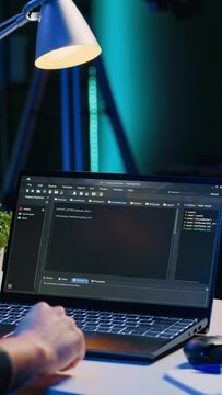 Vertical video Skilled computer scientist writes code on laptop screen while in living room office using programming languages. Self employed IT specialist working on fixing database errors from home