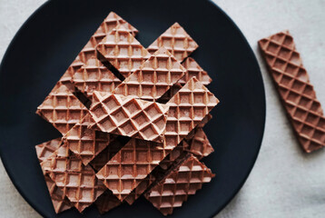 Chocolate wafers on a black plate on a gray background