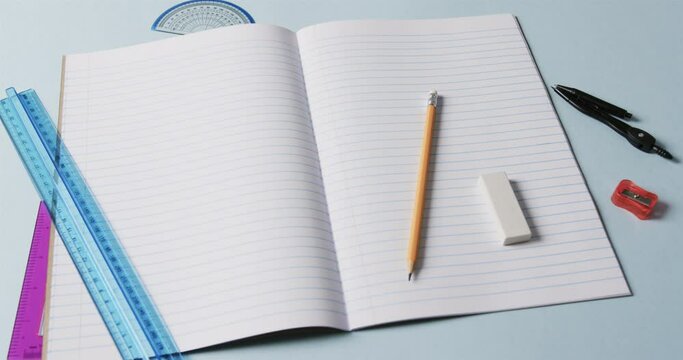 Close up of open notebook with school stationery on blue background, in slow motion