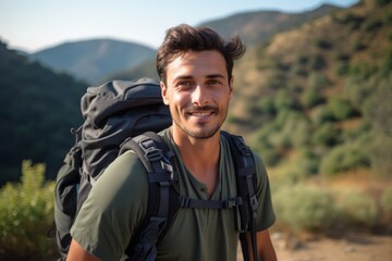 Portrait of a handsome young man with backpack standing in the mountains - obrazy, fototapety, plakaty
