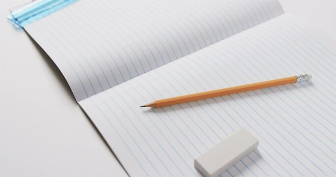 Close up of open notebook with school stationery on grey background, in slow motion