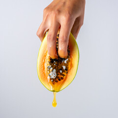 Two female fingers in papaya fruit with a dripping honey. Sex concept.