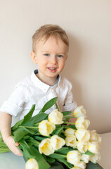 Obraz na płótnie Canvas Happy little boy holding a bouquet of white tulips. Mother's day