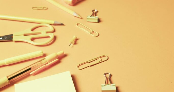 Close up of school stationery on orange background, in slow motion