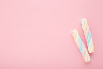 Two colorful swirl soft marshmallow candies on light pink table background. Pastel color. Sweet...