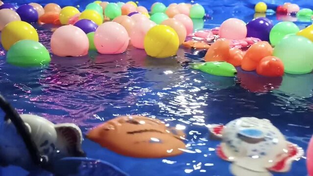 Ball Games And Children's Plastic Fish With Various Colors In The Blue Water Pool