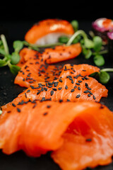 Variety of bright sushi rolls with greens on a black background. Incredible fresh sushi rolls on a dark background. Cooking traditional Japanese seafood and fish dishes.