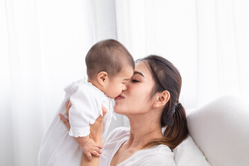 Fototapeta na wymiar Asian beautiful mom motherhood lie down nursing, kissing newborn baby infant toddler, gently hold together on chest with love, infant sleep comfortable with safe and protection by mother taking care