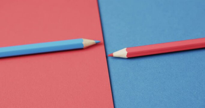 Close up of blue and red crayons arranged on red and blue background, in slow motion